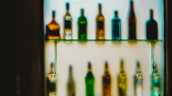 estante de un bar con botellas de licores, las botellas están distorsionadas por algún efecto de la cámara, distribucion de licores