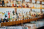 Barra de bar llena de botellas de distintas marcas de licores y destilados, distribución de bebidas